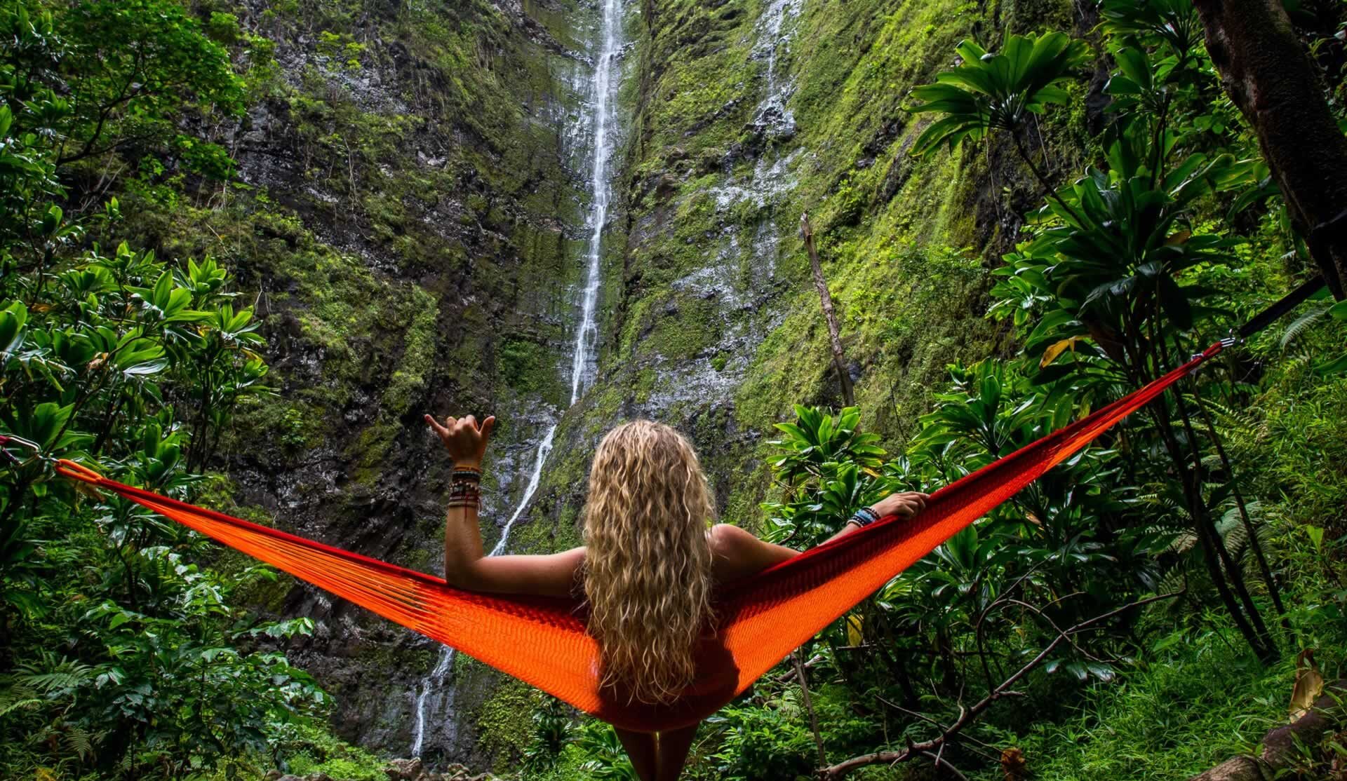 A lady sitting in a hammock with her back to the camera waving