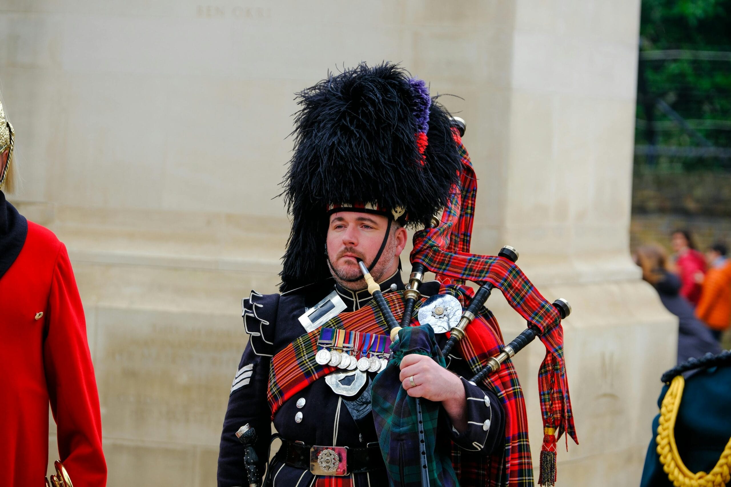 Scottish bagpiper in full ceremonial dress with medals, performing in England.